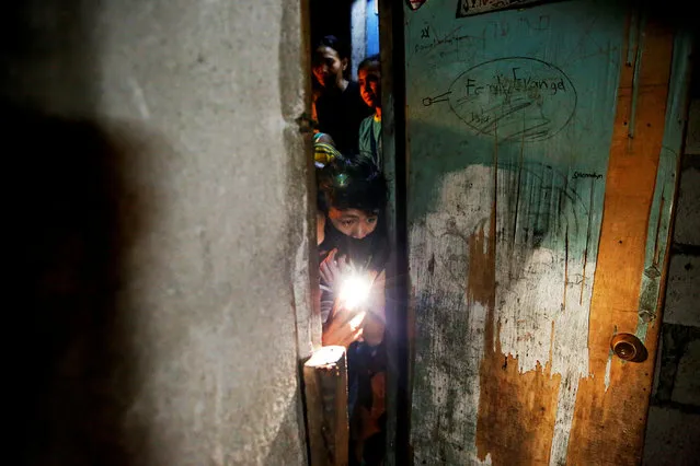 People look inside and take a pictures of a room in which five people were killed in Manila, Philippines early November 1, 2016. According to police and witnesses, unknown masked gunmen killed five people inside a house that is a known drug den. (Photo by Damir Sagolj/Reuters)