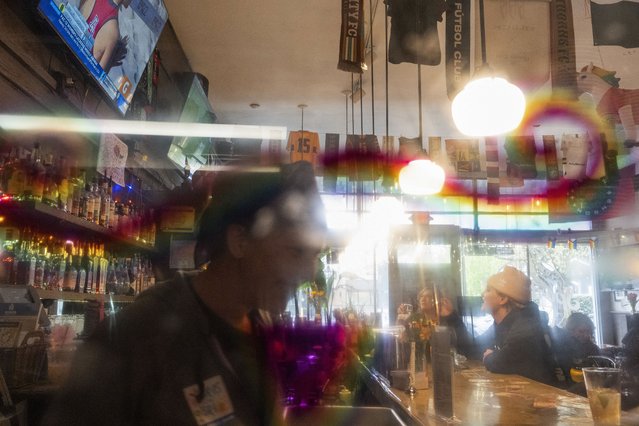 With a rainbow mustache drawn on a porthole door connecting the kitchen and bar, patrons watch a beach volleyball match on big-screen TV at The Sports Bra sports bar in Portland, Ore., April 24, 2024. (Photo by Jenny Kane/AP Photo)