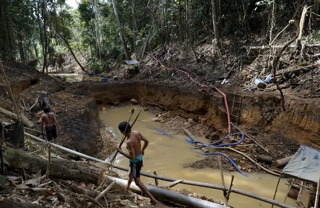 Yanomami indians follow agents of Brazil’s environmental agency in an illegal gold mine during an operation against illegal gold mining on indigenous land, in the heart of the Amazon rainforest, in Roraima state, Brazil April 17, 2016. (Photo by Bruno Kelly/Reuters)