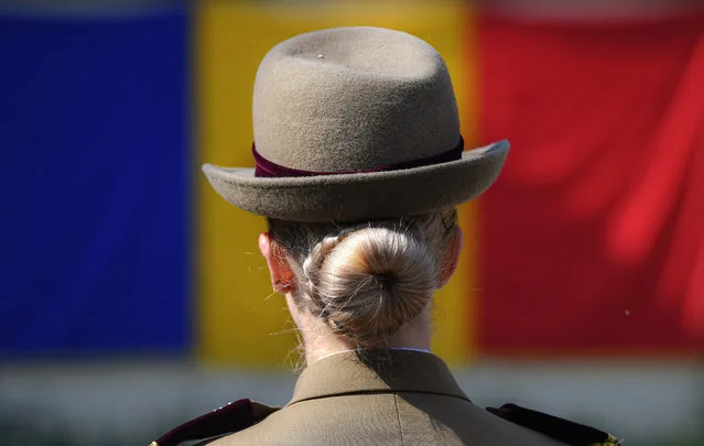 A Romanian military medic, backdropped by Romania's flag, attends a graduation ceremony in Bucharest, Romania, Friday, July 26, 2019. Students of Romania's Military Medical Institute celebrated after receiving their first military rank. (Photo by Andreea Alexandru/AP Photo)