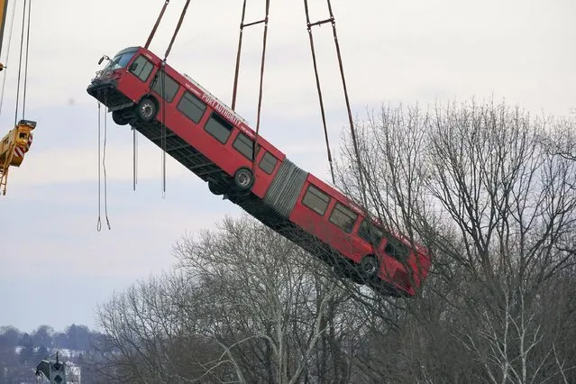 Cranes lift the bus that was on a bridge when it collapsed Friday during the recovery process on Monday January 31, 2022 in Pittsburgh's East End. (Photo by Gene J. Puskar/AP Photo)