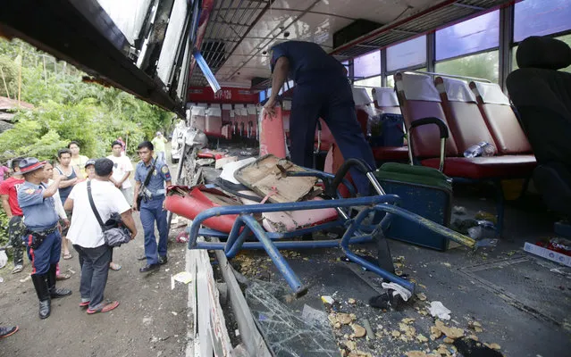 Police and rescuers inspect a passenger bus after it rammed into a cargo truck early Wednesday, April 16, 2014 along a highway at Libmanan township, Camarines Sur province, south of Manila, Philippines. Police said at least five passengers, including a child, were killed and 15 others were injured in the accident Wednesday which came as Filipinos flock to their hometowns for the Holy Week break. (Photo by Bullit Marquez/AP Photo)