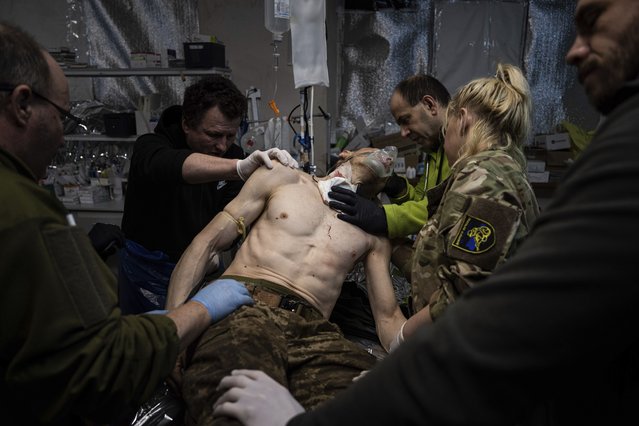 Ukrainian military medics treat their wounded comrade at the field hospital near Bakhmut, Ukraine, Sunday, February 26, 2023. (Photo by Evgeniy Maloletka/AP Photo)