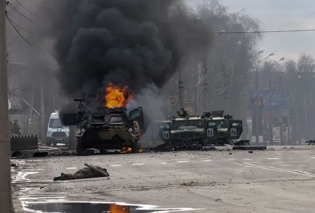 An armored personnel carrier burns and damaged light utility vehicles stand abandoned after fighting in Kharkiv, Ukraine, Sunday, February 27, 2022. The city authorities said that Ukrainian forces engaged in fighting with Russian troops that entered the country's second-largest city on Sunday. (Photo by Marienko Andrew/AP Photo)