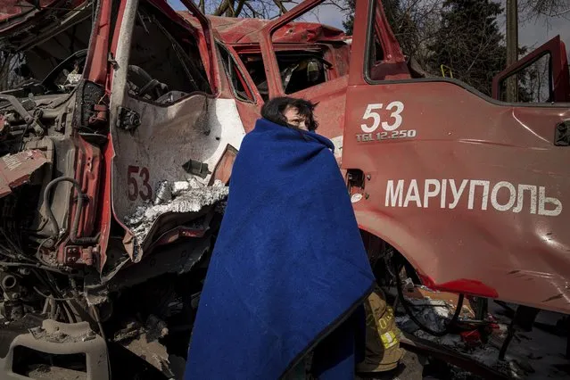 A women covers herself with a blanket near a damaged fire truck after shelling in Mariupol, Ukraine, Thursday, March 10, 2022. (Photo by Evgeniy Maloletka/AP Photo)