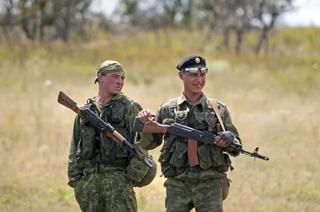 Russia-backed separatists stand at the site of the crashed Malaysia Airlines Flight 17 plane, near the village of Hrabove, eastern Ukraine, Thursday, July 16, 2015. The fighters said they have arrived to protect the media and make sure the MH17 crash site is clear of ammunition and mines. (Photo by Antoine E. R. Delaunay/AP Photo)