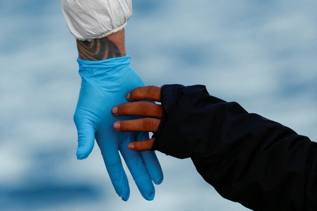 A migrant rescued by a merchant vessel is helped to disembark from a Malta Armed Forces patrol boat outside Marsaxlokk, Malta on April 17, 2023. (Photo by Darrin Zammit Lupi/Reuters)