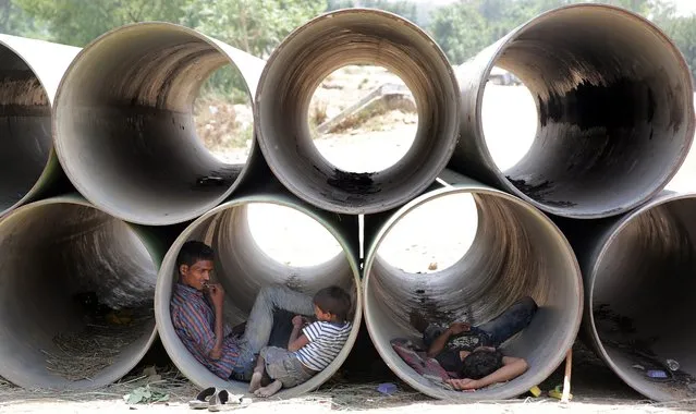 Indians rest in unused water pipes to avoid the heat on a hot summer day in New Delhi, India, 19 May 2016. According to the news reports an orange alert was announced in Delhi and non capital regions as temperatures in the Indian capital reached to the 47 degree Celcius. (Photo by Harish Tyagi/EPA)