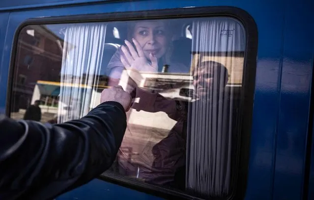 A woman waves to say good bye to her husband as she leaves on a bus, a day after a rocket attack at a train station in Kramatorsk, on April 9, 2022. At least 52 people were killed, including five children, following a rocket attack on April 8 on a train station in the eastern Ukrainian city of Kramatorsk that is being used for civilian evacuations, according to Donetsk region governor. (Photo by Fadel Senna/AFP Photo)