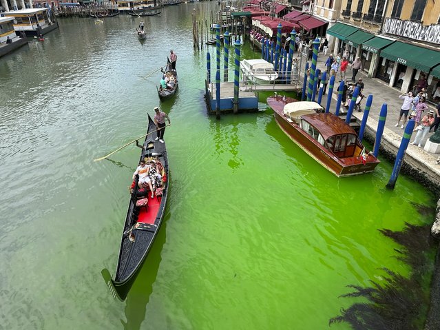 A bright patch of green is seen in the Grand Canal along an embankment lined with restaurants, in Venice, Italy, Sunday, May 28, 2023. Police in Venice are investigating the source of a phosphorescent green liquid patch that appeared Sunday in the city's famed Grand Canal. (Photo by Luigi Costantini/AP Photo)