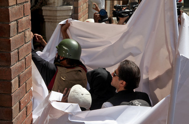 Pakistan's former Prime Minister Imran Khan and his wife Bushra Bibi are covered with a white sheet as they arrive to appear at the High Court in Lahore, Pakistan on May 15, 2023. (Photo by Mohsin Raza/Reuters)