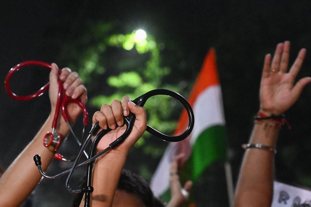 Medical professionals and activists hold stethoscopes and wave the flag of India as they take part in a midnight protest to condemn the rape and murder of a young medic, in Kolkata on August 14, 2024, on the eve of India’s 78th Independence Day celebrations. Indian doctors in government hospitals across several states halted elective services “indefinitely” on August 12 to protest the rape and murder of a young medic. (Photo by Dibyangshu Sarkar/AFP Photo)