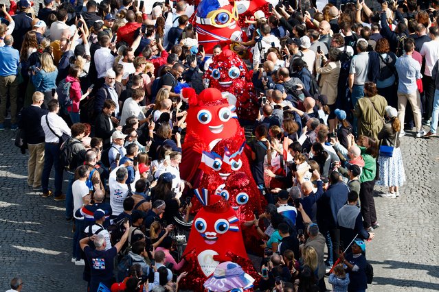 People gather around the Olympic “Phryge” mascots during a parade of French athletes who competed in the Paris 2024 Olympic and Paralympic Games on the Champs-Elysees avenue in Paris on September 14, 2024. (Photo by Gonzalo Fuentes/Pool via AFP Photo)