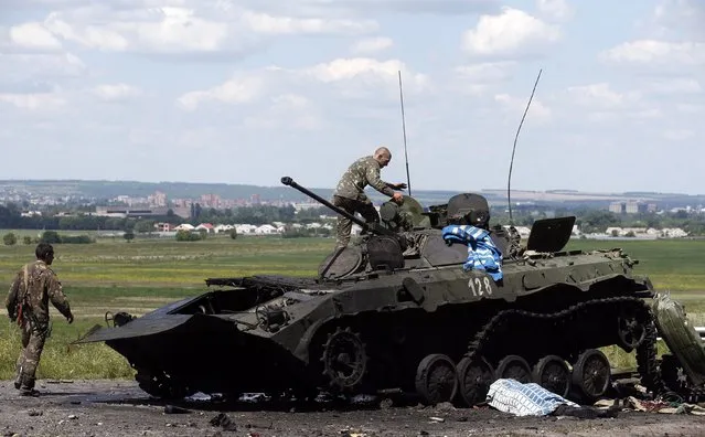 Ukrainian soldiers check a destroyed armoured vehicle at a Ukrainian Army checkpoint in the outskirts of the eastern Ukrainian town of Slaviansk July 5, 2014. Pro-Russian rebels were pulling out of a flashpoint area of eastern Ukraine on Saturday as authorities in Kiev savored a major military success in its three-month fight against the separatists. (Photo by Maxim Zmeyev/Reuters)