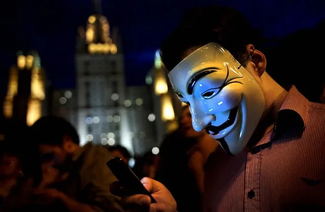 A masked protester tweets while listening to a speech at a new campsite for opponents of the government in Moscow on May 18, 2012