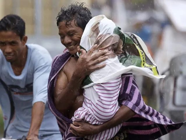 Residents of the slum community of Baseco evacuate to safer grounds at the onslaught of typhoon Rammasun in Manila Wednesday, July 16, 2014 in Manila, Philippines. Typhoon Rammasun left at least seven people dead and knocked out power in many areas Wednesday but the Philippine capital and densely populated northern provinces were spared a direct battering when its fierce winds shifted slightly. (Photo by Bullit Marquez/AP Photo)