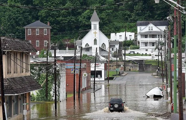 A vehicle makes a wake along the flooded Lower Oakford Ave. Friday, June 24, 2016, in Richwood, W.Va. (Photo by Rick Barbero/The Register-Herald)