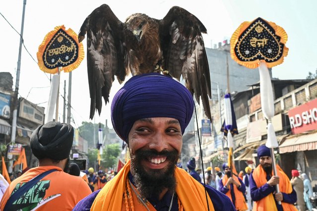 A Sikh devotee with an eagle takes part in a religious procession on the eve of the birth anniversary of the fourth Sikh Guru Ramdas in Amritsar on October 18, 2024. (Photo by Narinder Nanu/AFP Photo)