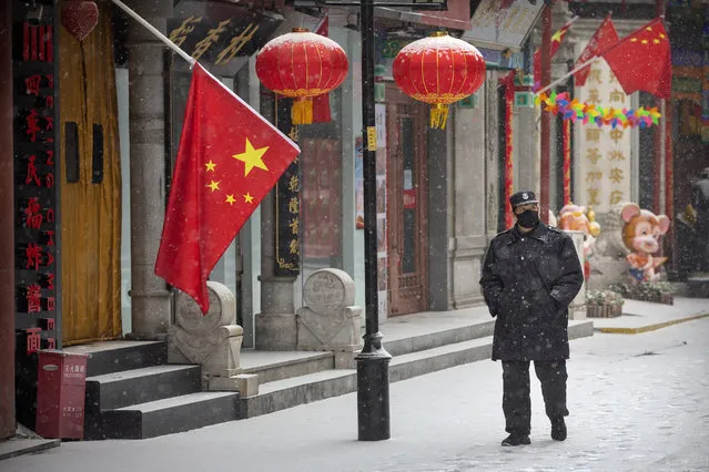 In this February 5, 2020, file photo, a security guard wears a face mask as he walks along a pedestrian shopping street during a snowfall in Beijing. China’s ruling Communist Party faces a politically fraught decision: Admit the outbreak of a new virus isn’t under control and cancel this year’s highest-profile official event. Or bring 3,000 legislators to Beijing next month and risk fueling public anger at the government’s handling of the disease. (Photo by Mark Schiefelbein/AP Photo/File)