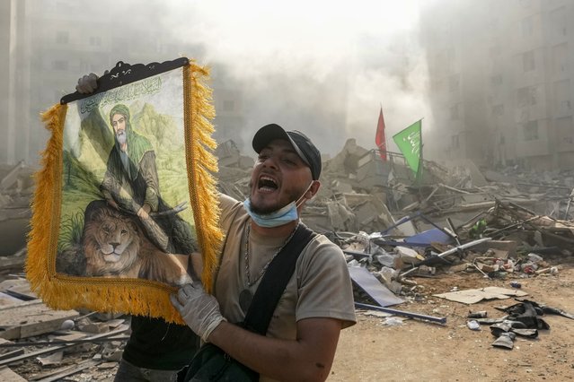 A man shouts slogans as he holds a picture depicting Imam Ali at the site of an Israeli airstrike in Dahiyeh, Beirut, Lebanon, Friday, November 1, 2024. (Photo by Hassan Ammar/AP Photo)