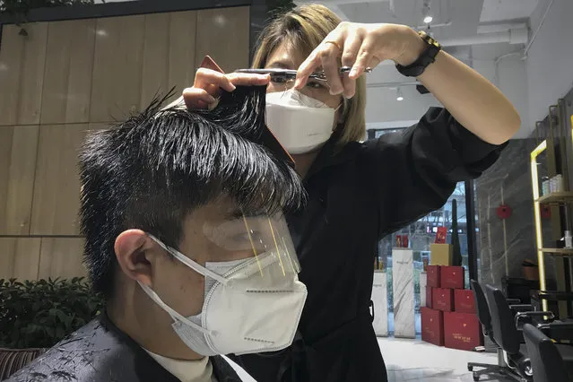 A barber wearing a protective face mask cuts a clients hair with an eye cover and face mask at a hair salon in Beijing, Monday, February 24, 2020. Monday is the second day of the second month of the Chinese lunar calendar, traditionally an auspicious time when people rush into barbershops to get new haircuts. Getting a fresh look on the day is thought to bring good luck for the year ahead, but getting a haircut has become a challenge in China now that most barbershops are temporarily shut to avoid public gatherings amid the virus outbreak. (Photo by Olivia Zhang/AP Photo)