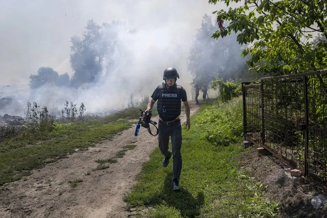 An AFP journalist runs as smoke rises behind after a bombardment in Bakhmut, Eastern Ukraine, on July 31, 2022. (Photo by Bulent Kilic/AFP Photo)