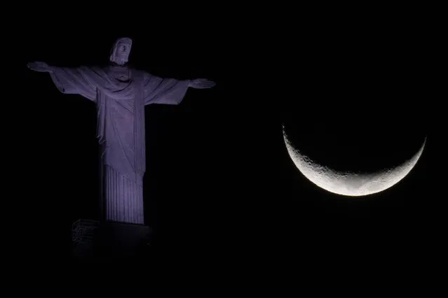 The crescent moon is seen next to the Christ The Redeemer statue in Rio de Janeiro, Brazil, on August 1, 2022. (Photo by Mauro Pimentel/AFP Photo)