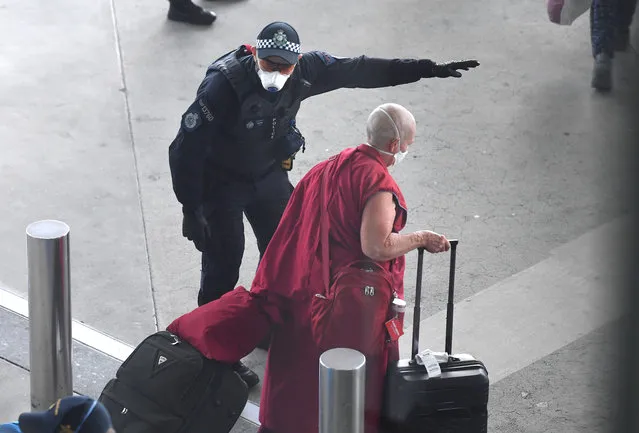 A police officer directs a returning passenger after arriving on a special Nepal Air flight repatriating Australian and New Zealanders from overseas, in Brisbane airport, Thursday, April 2, 2020. The chartered flight out of Nepal had 222 Australians and 28 New Zealand citizens and permanent residents onboard. (Photo by Dan Peled/AAP Image)