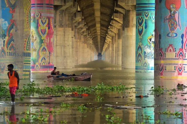Men rest on a boat in the overflowed Ganges River under the Shastri Bridge in Allahabad on August 17, 2022, as water levels of the Ganges and Yamuna rivers rose following monsoon rainfalls. (Photo by Sanjay Kanojia/AFP Photo)