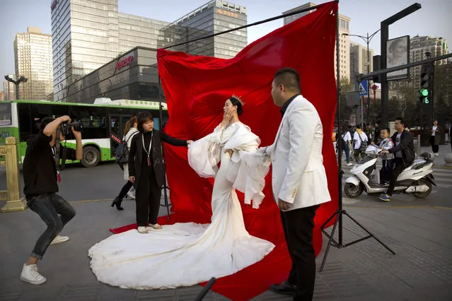 In this March 28, 2019, file photo a woman in wedding attire poses for a photo portrait along a busy street in Xi'an in northwestern China's Shaanxi Province. One of the ancient capitals of China, Xi'an is home to the world-renowned Terracotta Warriors. Chinese leaders have long been sensitive about their communist country’s international image. Now, they are battling back, investing in diplomacy and a courtship of hearts and minds, just as the United States digs in on the Trump administration’s “America First” mindset. (Photo by Mark Schiefelbein/AP Photo/File)