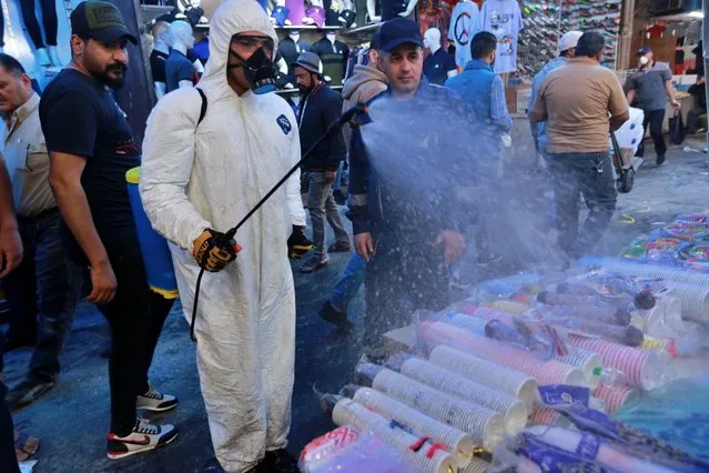 A civil defense worker wearing a protective suit sprays disinfectant as a precaution against the new coronavirus, in the main market, Baghdad, Iraq, Tuesday, March 10, 2020. For most people, the new coronavirus causes only mild or moderate symptoms, such as fever and cough. For some, especially older adults and people with existing health problems, it can cause more severe illness, including pneumonia. (Photo by Hadi Mizban/AP Photo)