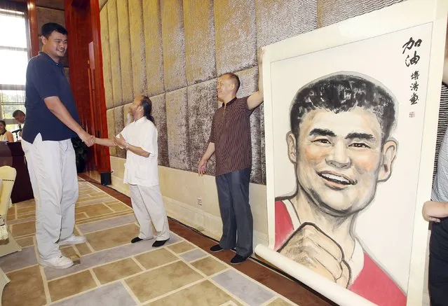 Former NBA basketball player Yao Ming (L) shakes hands with a Chinese artist as he receives a portrait of himself ahead of a charity basketball game organized by Yao Foundation, in Dongguan, August 31, 2014. (Photo by Reuters/Stringer)