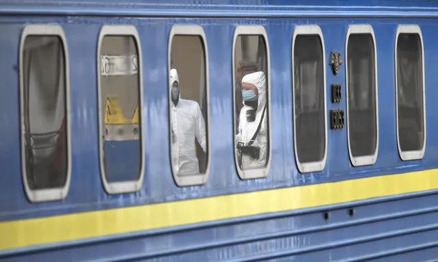 Medical workers are reflected in the windows of a carriage as they walk to check the passengers in a train with Ukrainians evacuated from Moscow at at Kiev railway station on March 29, 2020. Due to the situation with the novel coronavirus (COVID-19), a special train will be launched on the route Kiev – Moscow – Kiev to evacuate Russians from Ukraine and Ukrainians from the Russian Federation ahead of Ukrainian and Russian borders closing. (Photo by Sergei Supinsky/AFP Photo)