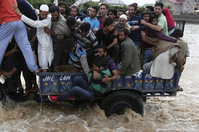 Kashmiri people hold a man as he falls from a tractor evacuating flood victims to higher grounds, as they move through a flooded street in Srinagar September 9, 2014. The prime ministers of India and Pakistan have offered to help each other in efforts to alleviate flood havoc in the disputed Himalayan region of Kashmir, lowering tension between the rival nations after weeks of army clashes and heated rhetoric. (Photo by Adnan Abidi/Reuters)