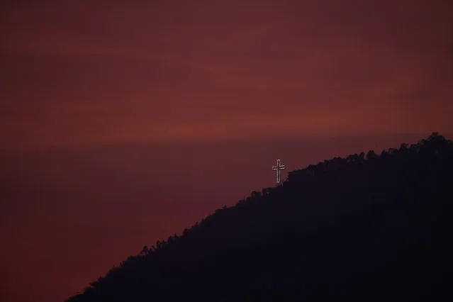 The “Cruz del Avila” shines on one of the peaks of El Avila at sunset during Holy Week in Caracas, Venezuela, Wednesday, April 8, 2020. (Photo by Matias Delacroix/AP Photo)