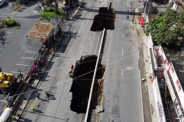 Aerial view of two giant holes in a road, caused by the collapse of a drainage system due to heavy rains that hit the country, in Villa Nueva, 15 km south of Guatemala City, on September 25, 2022. Four people traveling in a car suffered injuries and were taken to a hospital after they fell into a giant hole in a road, rescuers said. (Photo by Johan Ordonez/AFP Photo)