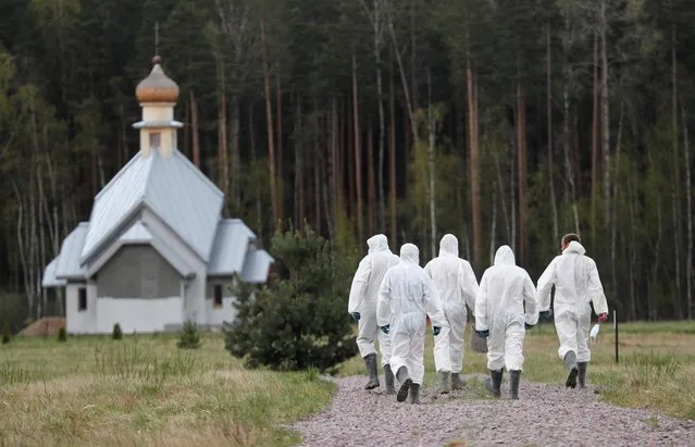Grave diggers wearing personal protective equipment (PPE) walk away after burying a person, who presumably died of the coronavirus disease (COVID-19), in the special purpose section of a graveyard on the outskirts of Saint Petersburg, Russia on May 13, 2020. (Photo by Anton Vaganov/Reuters)