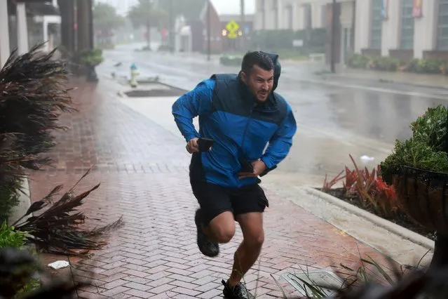 Brent Shaynore runs to a sheltered spot through the wind and rain from Hurricane Ian on September 28, 2022 in Sarasota, Florida. Ian made landfall this afternoon, packing 150-mile-per-hour winds and a 12-foot storm surge and knocking out power to nearly 1.5 million customers, according to published reports. (Photo by Joe Raedle/Getty Images/AFP Photo)