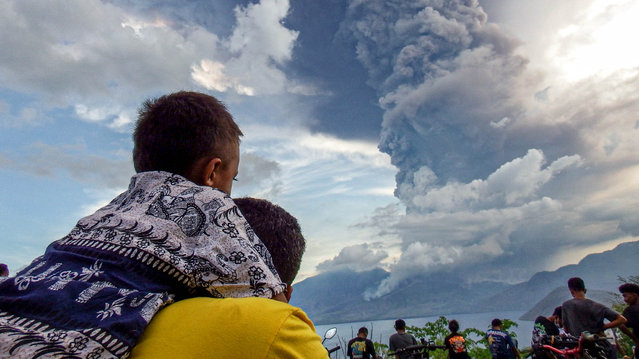 Residents watch the eruption of Mount Lewotobi Laki Laki from Eputobi village in Titihena, East Nusa Tenggara, on November 8, 2024. (Photo by Bayu Ismoyo and Arnold Welianto/AFP Photo)