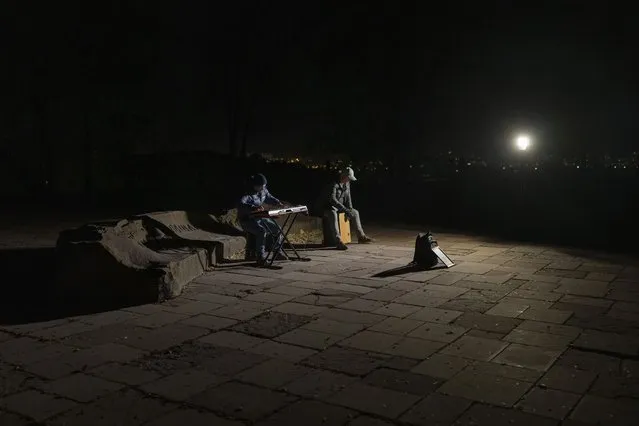Street musicians play their instruments in a square without electric lights in Kyiv, Ukraine, Tuesday, October 18, 2022. (Photo by Emilio Morenatti/AP Photo)