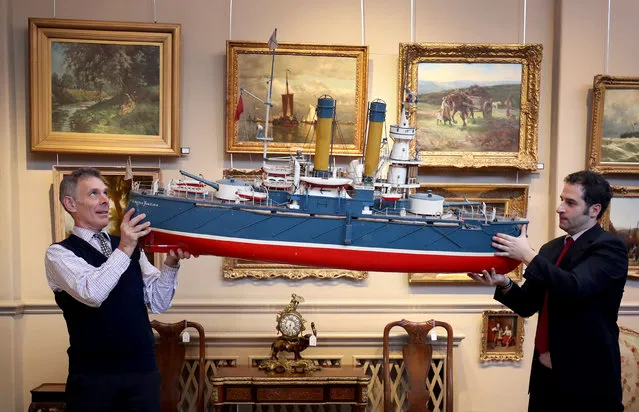 Charles Graham-Campbell (left) and Kenneth Naples, from Bonhams auction house, carry a model of the Russian ship “Admiral Oushavov” which is one of many late 19th Century and early 20th Century nautical items set to be auctioned at the Bonhams Home and Interiors sale in Edinburgh on November 10, 2017. (Photo by Jane Barlow/PA Images via Getty Images)