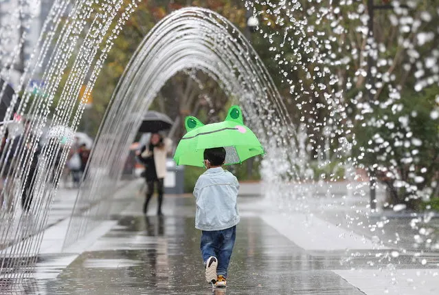 A child walks through a fountain tunnel in Seoul, South Korea, 09 October 2022, as he holds an umbrella on a rainy day. (Photo by Yonhap/EPA/EFE)