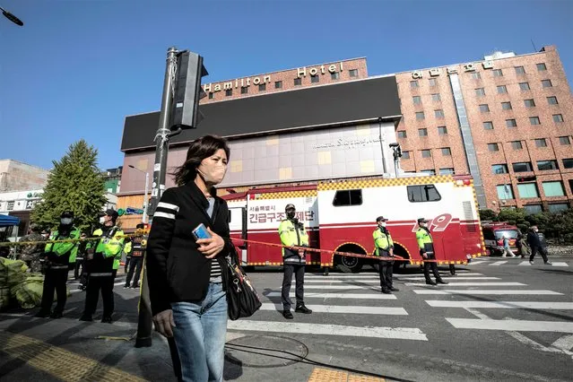 A woman walks past the police who stand guard near the accident site in Itaewon in Seoul, South Korea on October 30, 2022. (Photo by Jean Chung for The Washington Post)