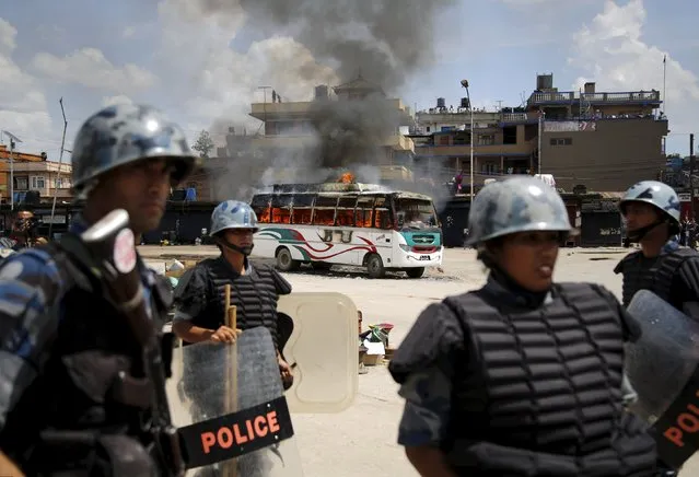 Members of Nepalese Armed Police Force stand in front of a burning passenger bus after it was set on fire by unidentified protesters during the nationwide strike, called by the opposition parties against the proposed constitution, in Kathmandu, Nepal September 20, 2015. (Photo by Navesh Chitrakar/Reuters)