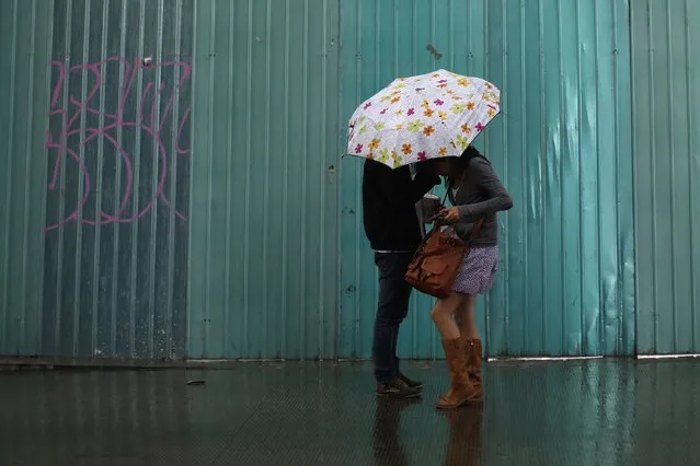 A couple shelters under an umbrella as it rains in downtown Mexico City October 2, 2014. (Photo by Tomas Bravo/Reuters)