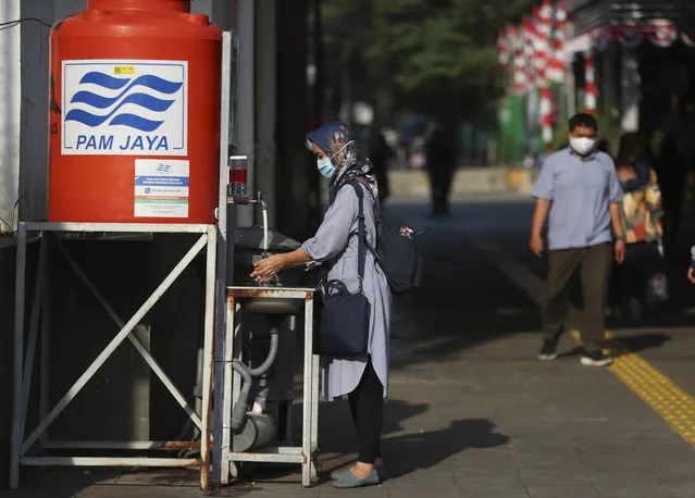 A women washes her hands to help curb the spread of the coronavirus in Jakarta, Indonesia, Monday, July 20, 2020. The number of coronavirus cases in Indonesia surpassed 50,000 in June, an increase that is worrying experts at a time when the government is allowing businesses to reopen amid increasing economic pressure. (Photo by Achmad Ibrahim/AP Photo)