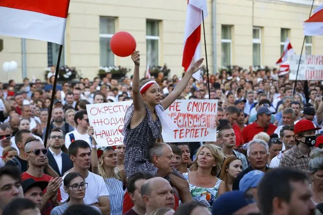 A girl gestures carried above the crowd as people gather outside a detention center during opposition rally in Minsk, Belarus, Monday, August 17, 2020. After the police crackdown and reports of abuse provoked widespread anger, the authorities backed off, allowing big weekend protests and releasing many of the detainees. The Interior Ministry said that just 122 detainees were still in custody as of Monday, and crowds rallied outside a prison in Minsk to press for their release. The poster reads “We could not tolerate more”. (Photo by Sergei Grits/AP Photo)
