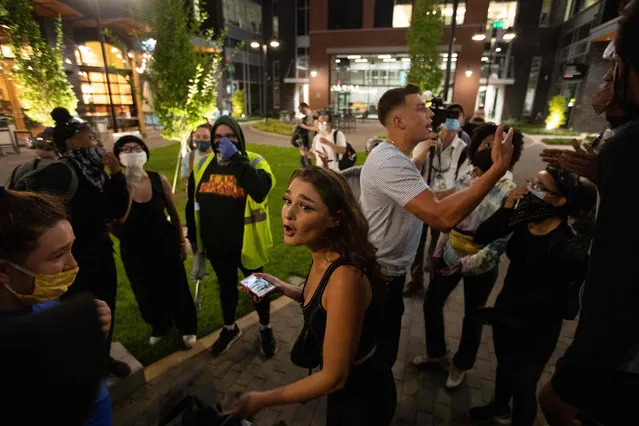 A man and woman argue with a group of protestors that marched into a courtyard where people were eating dinner in Charlotte's South End neighborhood during a protest organized by Charlotte Uprising near the site of the 2020 Republican National Convention in North Carolina on August 22, 2020. Delegates are holding private meetings inside the convention center ahead of the official start of the paired down convention on August 24. (Photo by Logan Cyrus/AFP Photo)