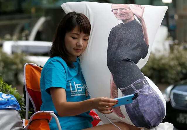 Ayano Tominaga holds a cushion printed a portrait of Apple co-founder Steve Jobs on it, as she sits in queue for the release of Apple's new iPhone 7 and 7 Plus in front of the Apple Store in Tokyo's Omotesando shopping district, Japan, September 16, 2016. (Photo by Issei Kato/Reuters)