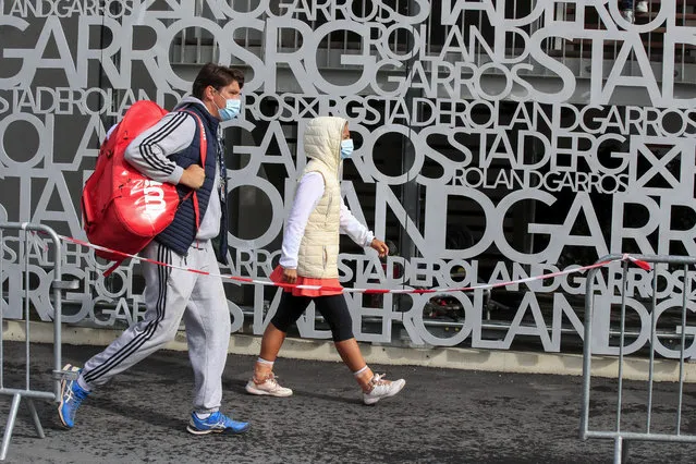 Serb's Natalija Kostic, right, and her coach Nicola Stevanovic wearing face masks to prevent the spread of coronavirus walk past a sign at at the Roland Garros stadium in Paris, Friday, September 25, 2020. Already repeatedly trimmed, crowd sizes for the French Open have been reduced again to just 1,000 spectators per day because of the worsening coronavirus epidemic in Paris. (Photo by Michel Euler/AP Photo)